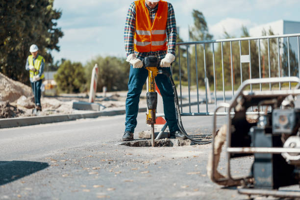 istock Worker with a pneumatic hammer breaking asphalt at road construction site 998457058