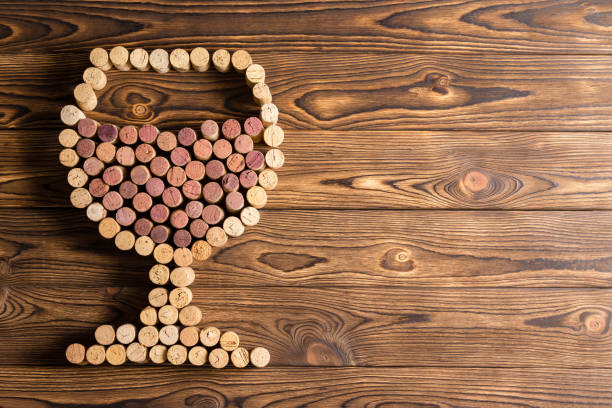 Creative design of a full wineglass made with corks from red and white wine bottles on a rustic wood background with copy space
