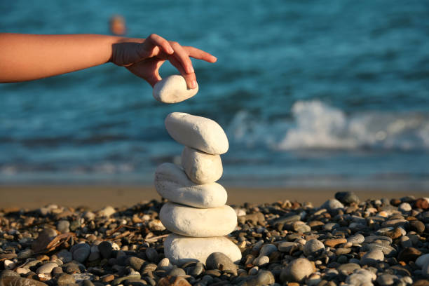 istock Teenager boy playing with stones on beach 998477080