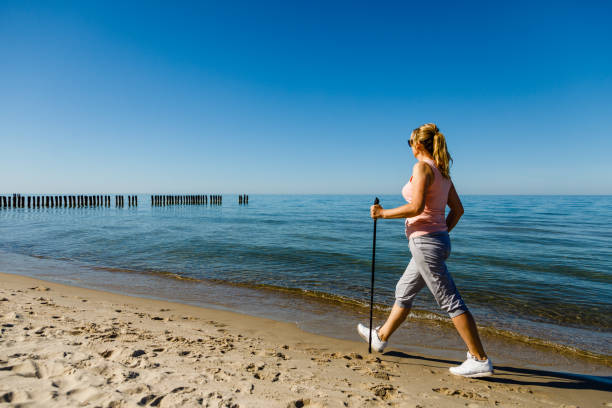 ノルディックウォーキング - ビーチでのトレーニング - nordic walking walking relaxation exercise women ストックフォトと画像