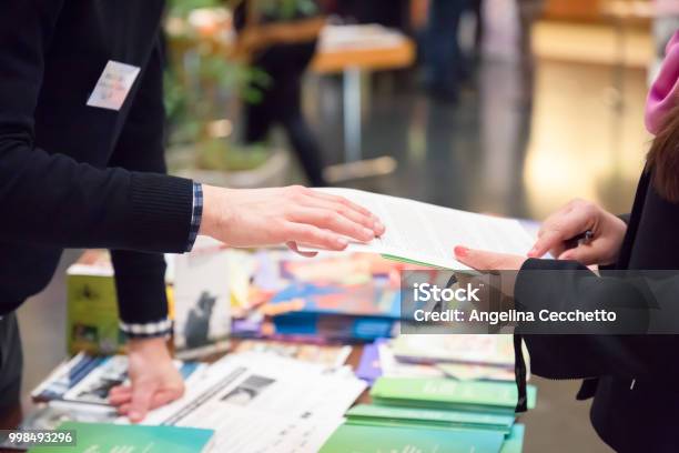 Man And Woman Sharing Information Leaflet Over Exhibition Stand Stock Photo - Download Image Now