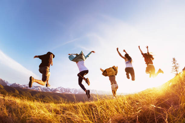 Group happy friends runs and jumps mountains sunset Group of five happy friends runs and jumps against mountains at sunset time. Travel or expeditions concept group mountain silhouette stock pictures, royalty-free photos & images