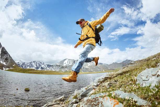 istock Hiker jump from big rock against mountains lake 998506030