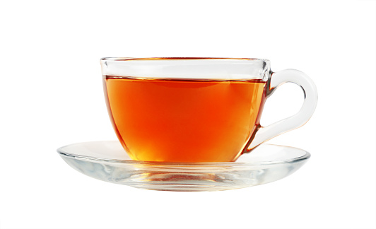 Close up one transparent glass cup of black tea on saucer isolated on white background, low angle side view