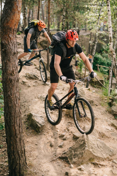 istock extreme young trial bikers riding downhill on back wheels at beautiful forest 998545792
