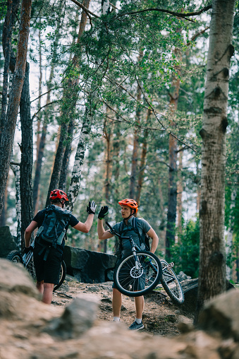 young trial bikers giving high five at beautiful forest