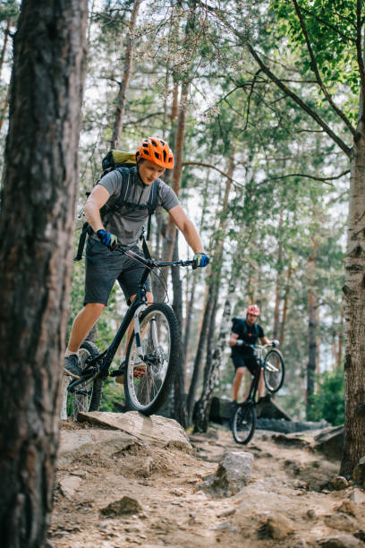 istock young trial bikers riding and performing stunts at beautiful forest 998545928