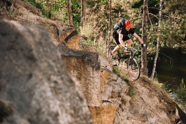 istock young trial biker riding downhill outdoors in pine forest 998550174