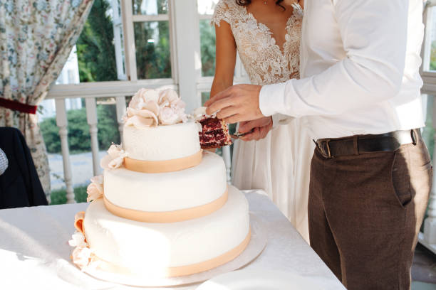 istock A bride and a groom is cutting their multi level white wedding cake 998567396