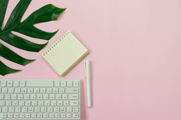 istock Top view flat lay with ,keyboard,a pen,notebook this object it for accounting,finance and business concept on soft pink and green leaf background. 998567620