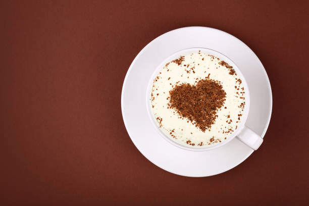 istock Full white cup of cappuccino coffee on brown 998570858