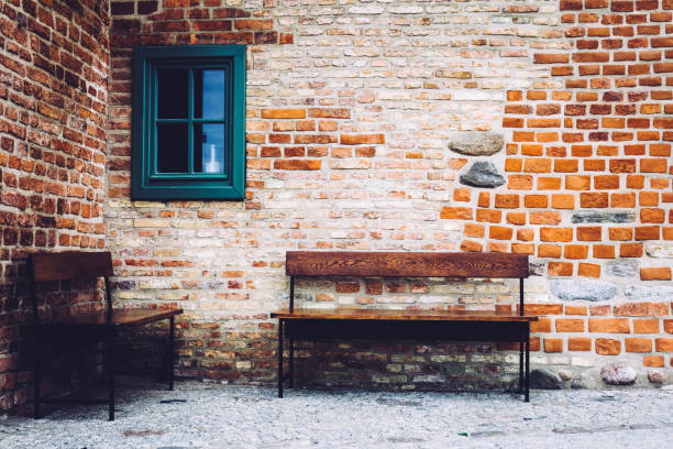 Two wooden benches standing in front of old brick building with green window. Old Town, Gdansk, Poland.
