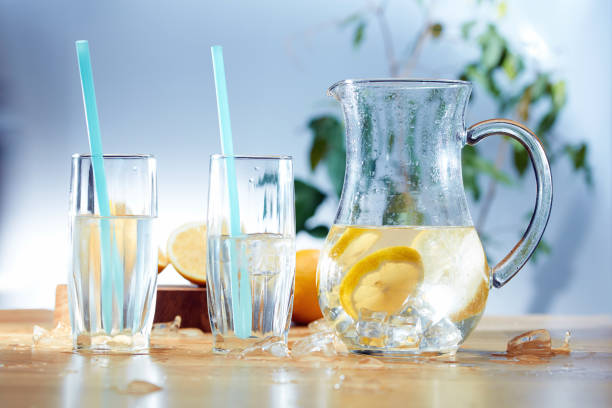 istock Decanter with sliced lemon, ice and glasses on wooden background 998613606