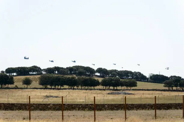 A few Eurocopter Super Puma helicopters flying in line over a farm
