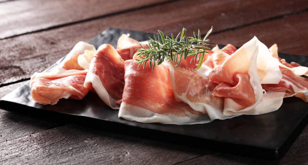 istock Italian prosciutto crudo or jamon with rosemary. Raw ham 998632604