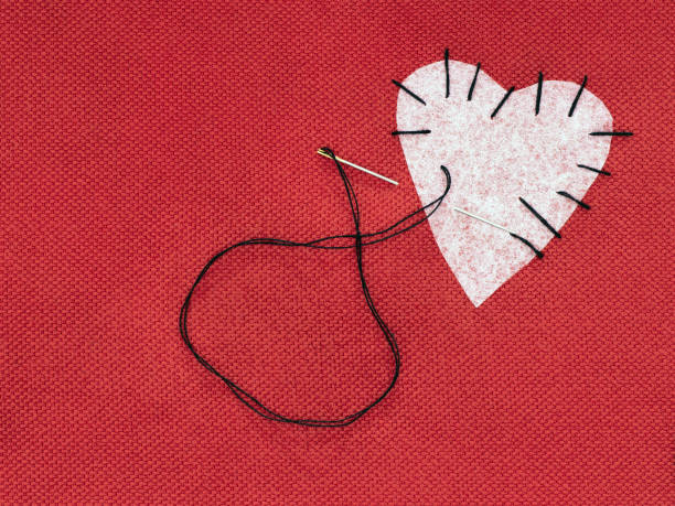 Fabric heart red with white patch and black sewing thread. Mend that broken heart concept.