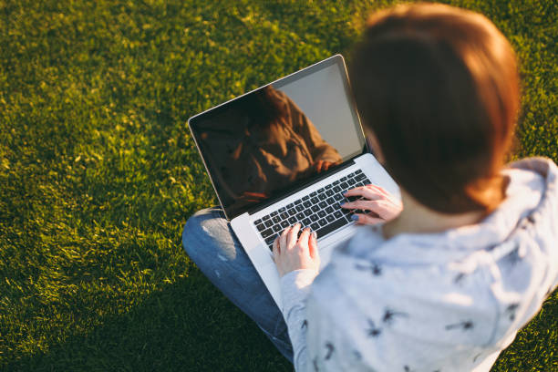 istock Close up hands on keyboard. Woman working on laptop pc computer with blank black empty screen to copy space in park on green grass sunshine lawn outdoors. Mobile Office. Freelance business concept. 998663152