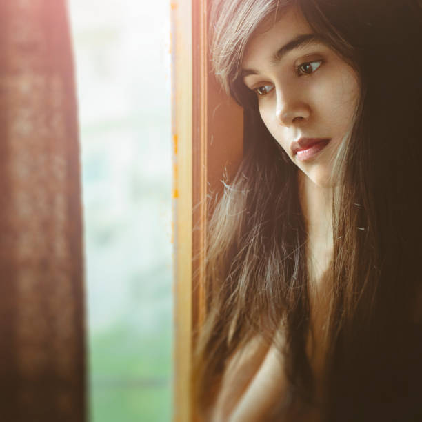 istock Beautiful serene young woman thinks near window. 998671580