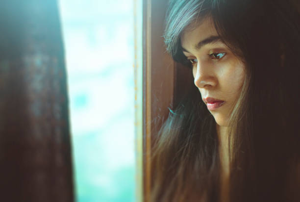 istock Beautiful serene young woman thinks near window. 998671584