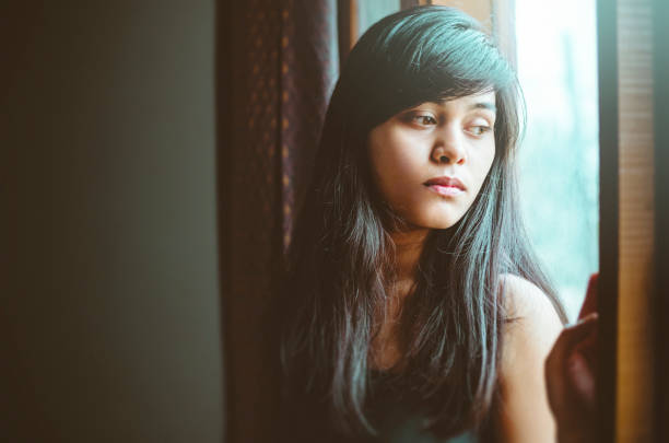 istock Beautiful serene young woman thinks near window. 998671590