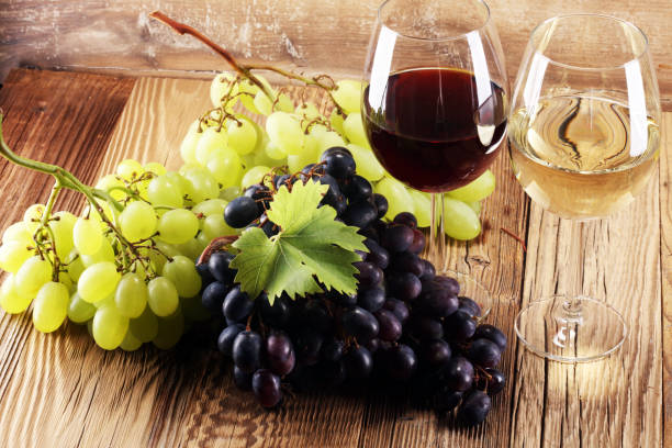 istock Red Wine and white wine with grapes and glasses on rustic background. 998684680