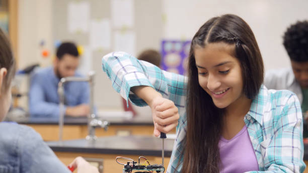 istock Confident preteen girl assembles robotics kit at school 998687848