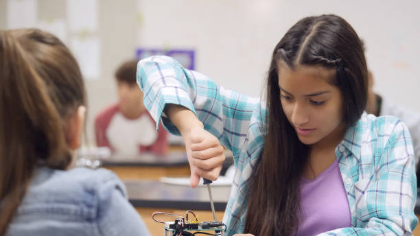 istock Preteen girl assembles robotics kit at school 998687904