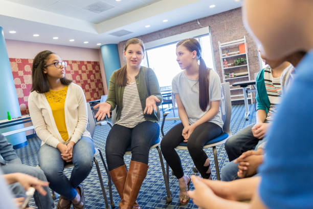 Teenage girl talks during support group meeting Caucasian teenage girl gestures as she talks about something during group therapy or support group session. teenagers only stock pictures, royalty-free photos & images
