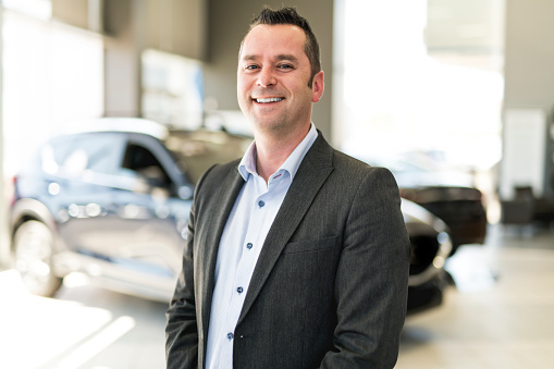 A Business man working at a car dealer smiling