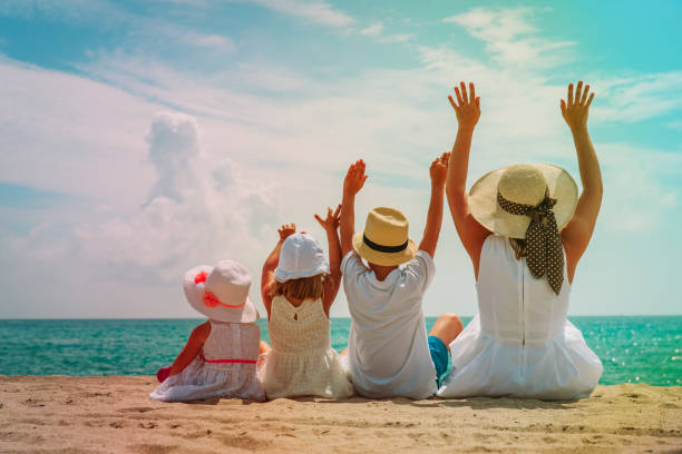 istock happy mother with kids hands up on the beach 998703152