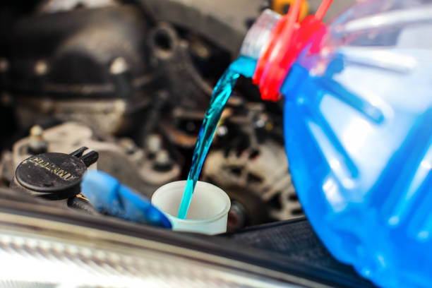 detail auf frostschutzmittel auto bildschirm waschen flüssigkeit gießen in schmutzigen auto aus blau und rot anti-freeze-wasserbehälter. - window frozen car cold stock-fotos und bilder