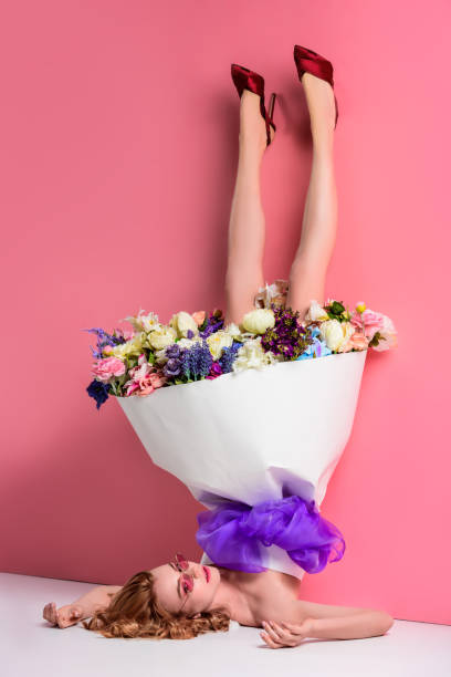 upside down view of beautiful young woman with fresh flowers in dress on pink - garment fragility women skirt imagens e fotografias de stock