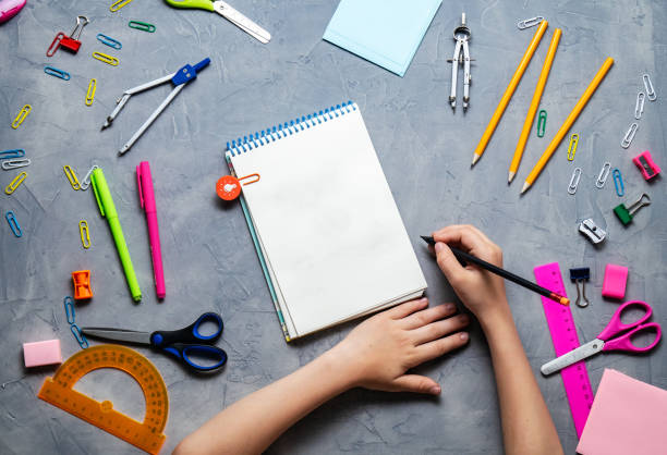 istock Back to School: Stationery and children's hands on a dark table. 998716054