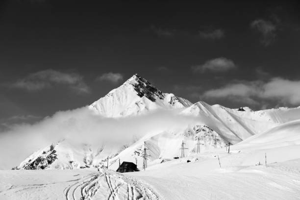 istock Black and white view on snowy ski slope and mountains 998832650
