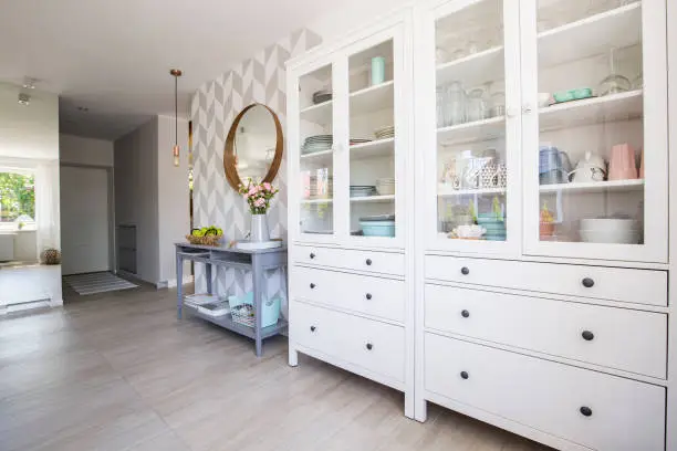 Photo of White kitchen cupboard with pastel dishes and blue console table