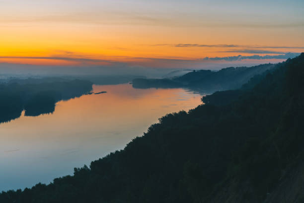 istock View from high shore on river. Riverbank with forest under thick fog. Gold dawn reflected in water. Yellow glow in picturesque predawn sky. Colorful morning atmospheric landscape of majestic nature. 998848204