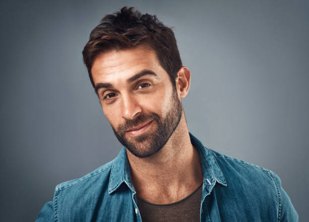 Unshaven but still as smooth as ever Studio portrait of a handsome young man posing against a grey background smirking stock pictures, royalty-free photos & images