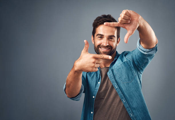 Gorgeous! I just have to take your picture Studio portrait of a handsome young man making a finger frame against a grey background hand cropping photos stock pictures, royalty-free photos & images