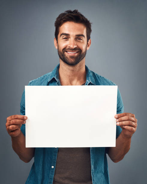 Your message matters Studio shot of a handsome young man holding a blank placard against a grey background placard photos stock pictures, royalty-free photos & images