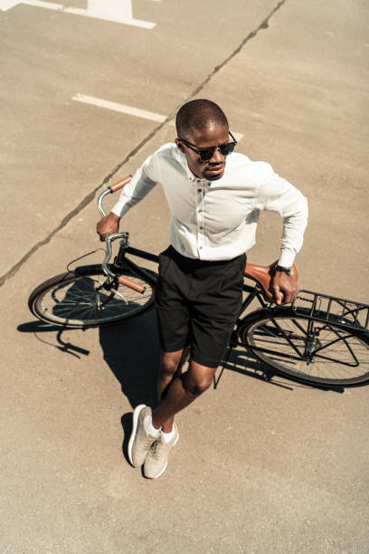 istock Stylish man wearing white shirt leaning on his bicycle 998855458