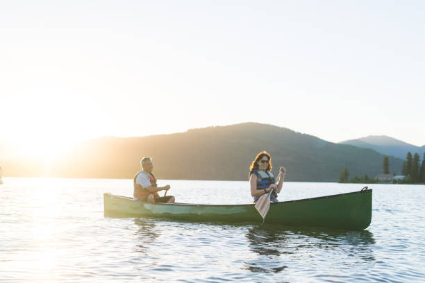 istock Older couple canoe together on a lake at sunset 998858856
