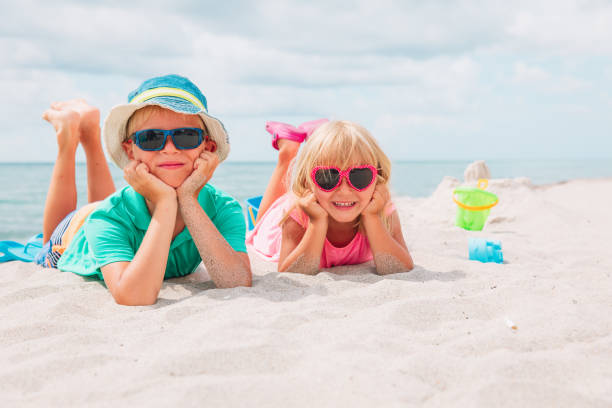 istock cute boy and girl play with sand on beach 998872476