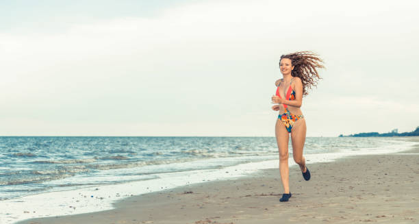 istock Attractive woman runs on sand beach in summer. 998882132