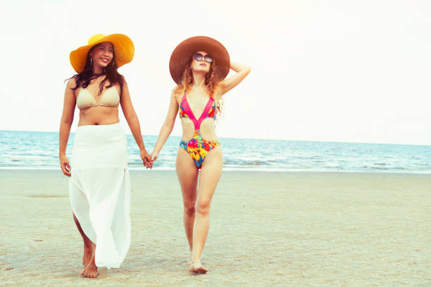 istock Happy women go sunbathing at sand beach in summer. 998885264