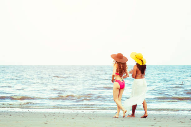 istock Happy women go sunbathing at sand beach in summer. 998885272
