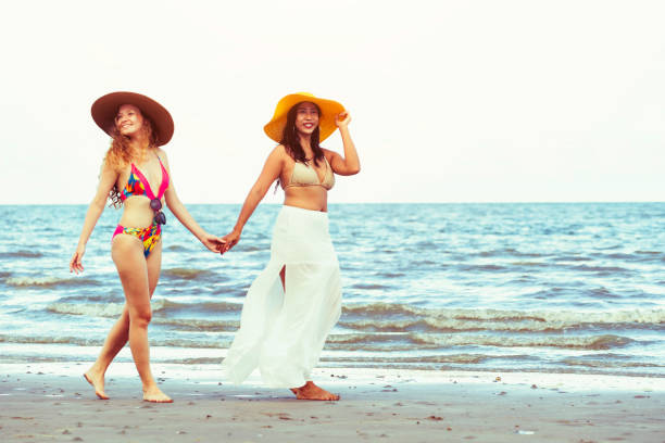 istock Happy women go sunbathing at sand beach in summer. 998885288