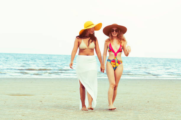 istock Happy women go sunbathing at sand beach in summer. 998885304
