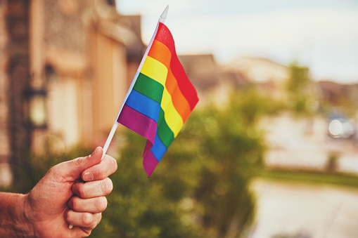 Male hand holding rainbow flag