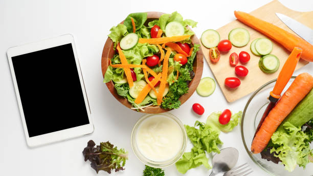 istock Tablet with blank screen and mixed vegetables salad on white background. 998913188
