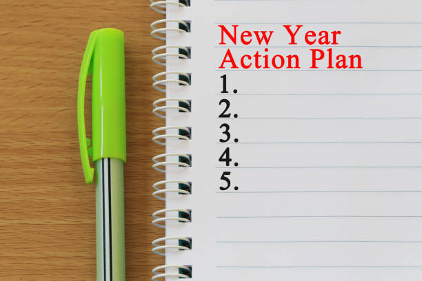 istock Notebooks and new year action plan text  are placed on a brown wooden floor. 998923256
